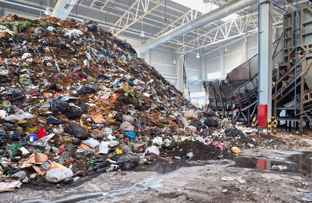 Solving problem of environmental pollution with waste at garbage processing plant - huge pile of garbage prepared for loading to conveyor belt for further sorting and processing, with copyspase.